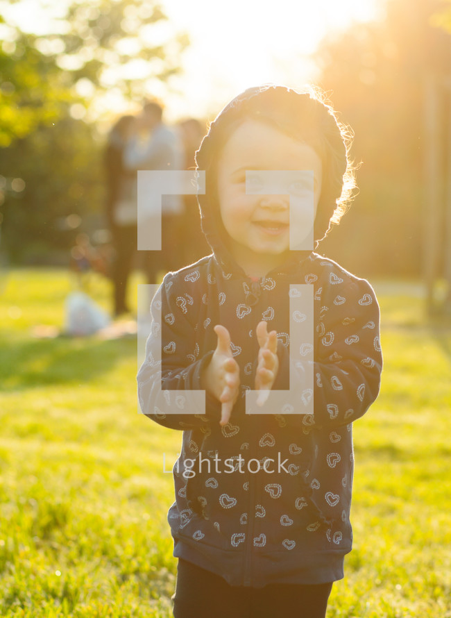 toddler girl plays happy in the park outdoors in the spring in backlight.