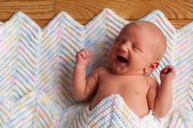 Newborn baby laying on a crochet blanket