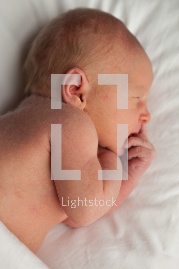 profile of a newborn baby laying on a white blanket