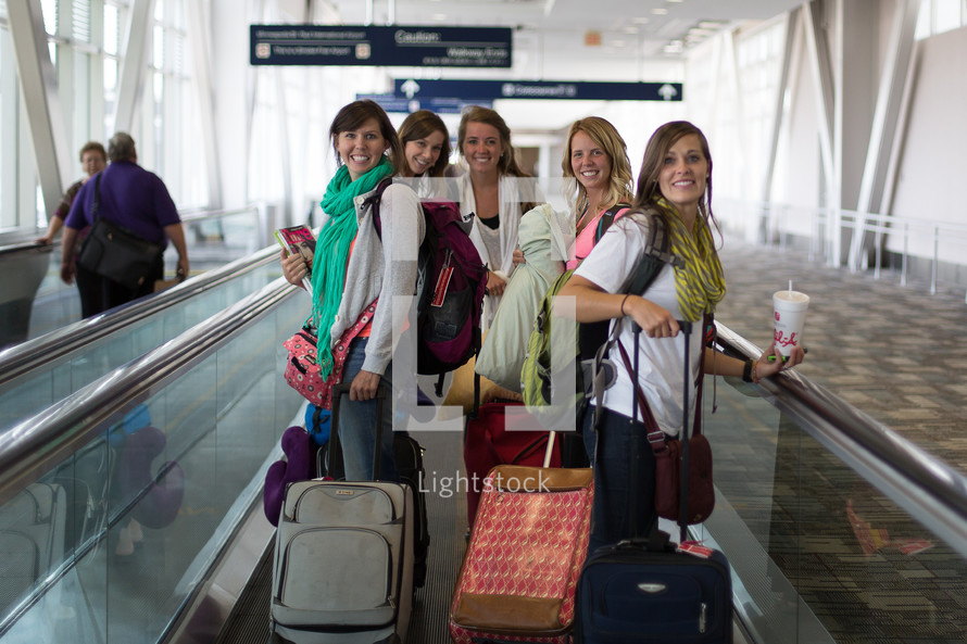 A group of young women walking through the airport with their suitcases