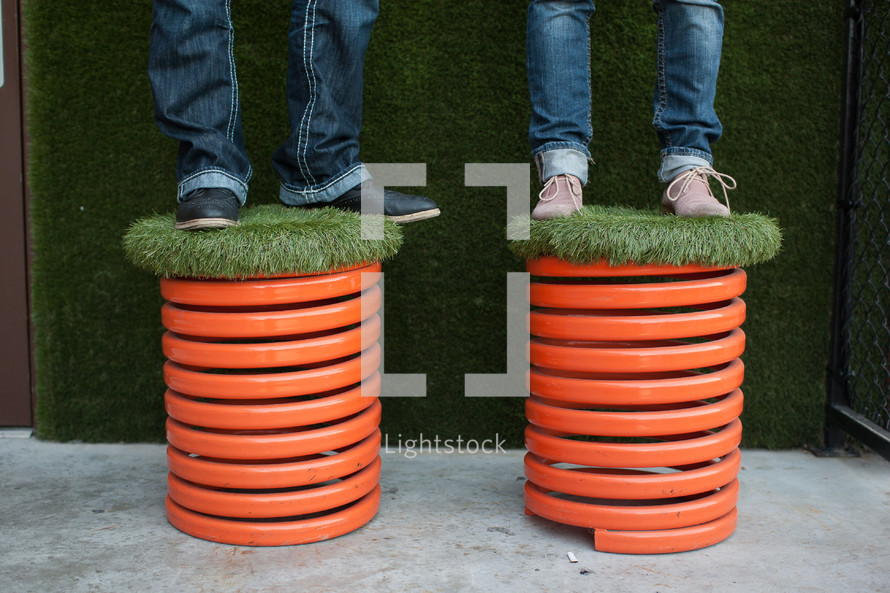 man and woman standing on turf grass covered stools