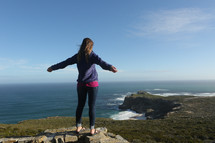 Woman standing on cliff overlooking ocean