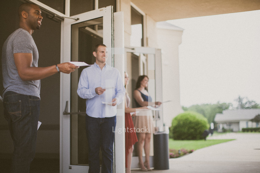 greeters handing out church bulletins at a church entrance