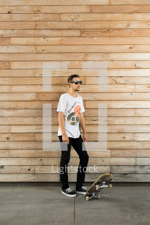 Man wearing sunglasses with a skateboard.