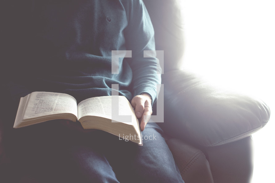 a man reading a Bible on his lap 