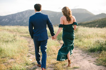a couple walking holding hands on a mountaintop 