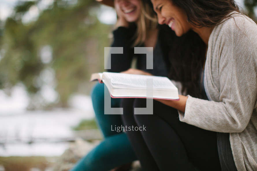 friends reading a Bible together outdoors 