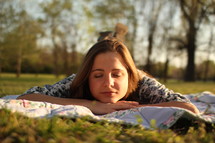 a woman sleeping on a blanket in the grass