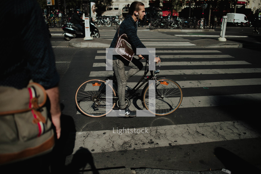 a man on a bicycle crossing over a crosswalk in a city 