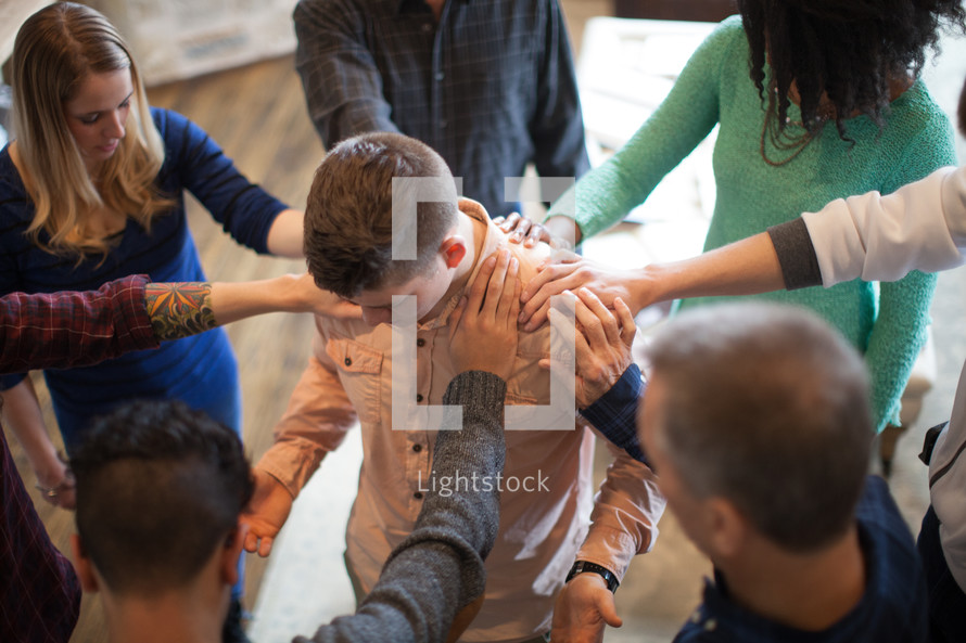 a groups hands on a man in prayer 