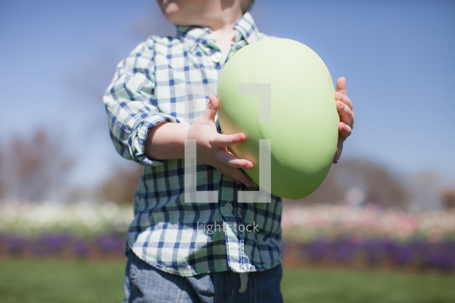 Boy holding a giant Easter egg.