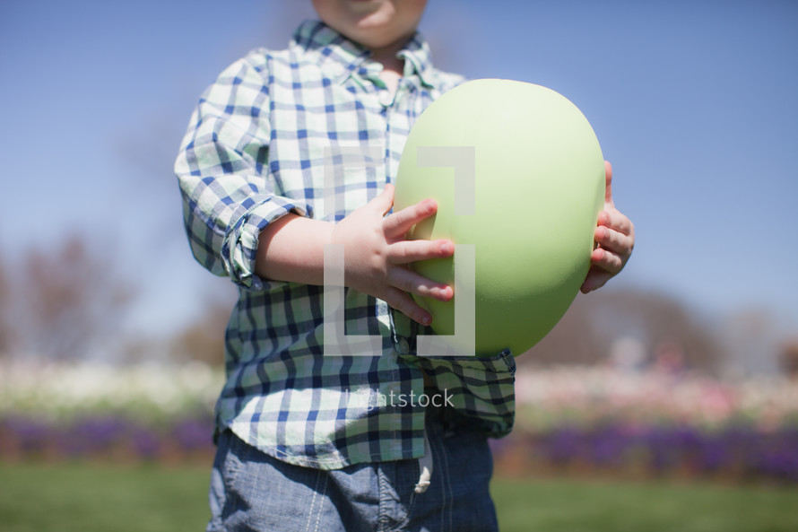 young boy holding a large Easter egg