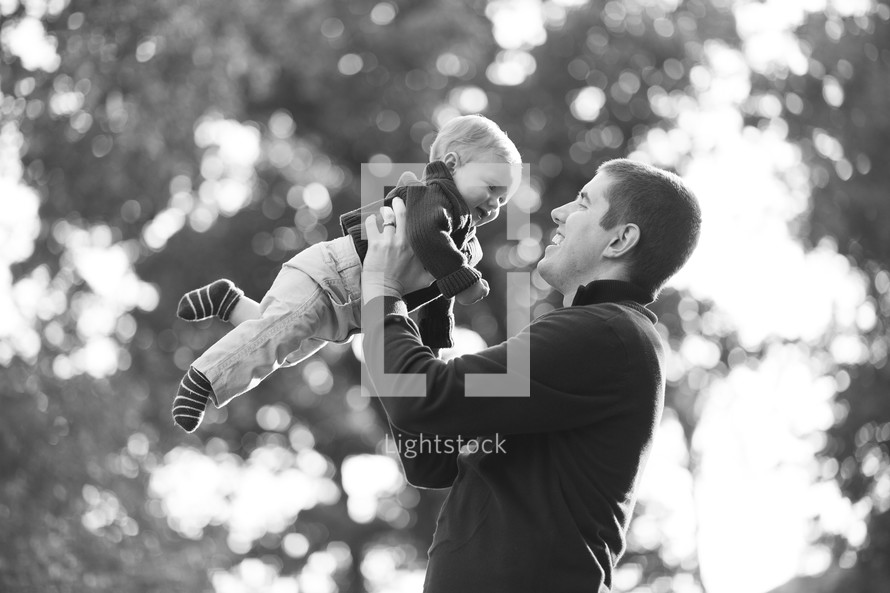 father holding a boy baby in the air