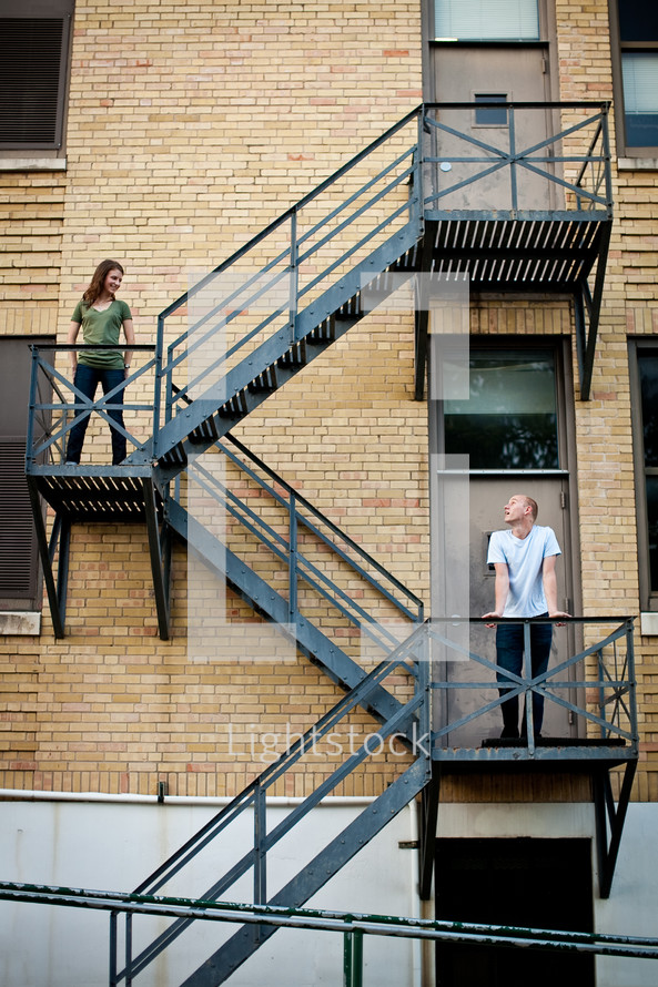 A couple stands on different flats on a stairwell