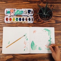 Painting with watercolors at a wooden table.

