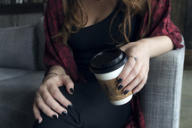 A young woman with black painted nails holding a coffee cup 