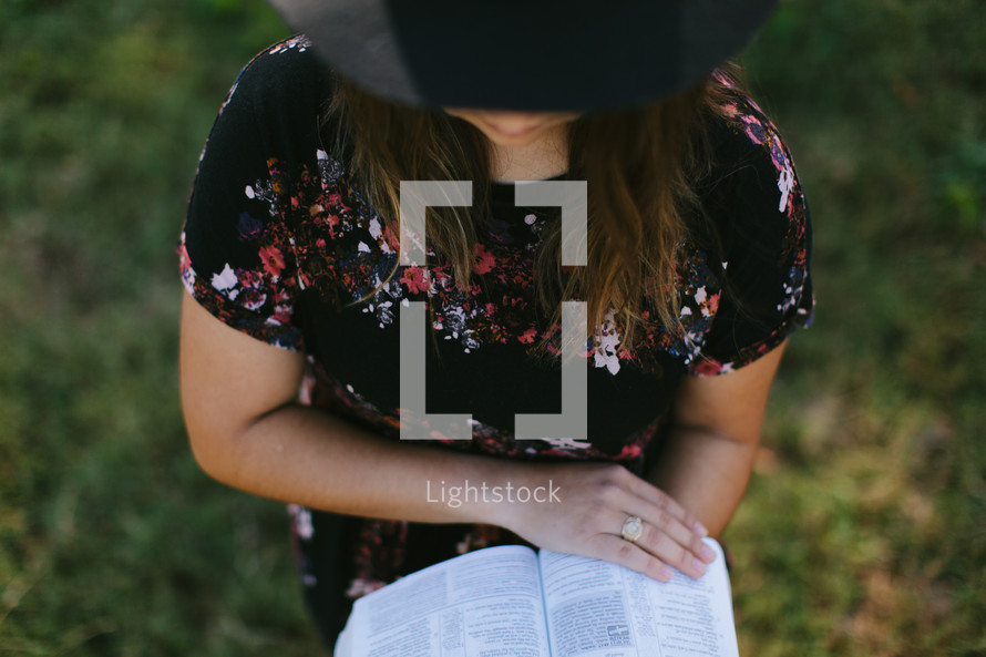 a woman in a hat reading a Bible 