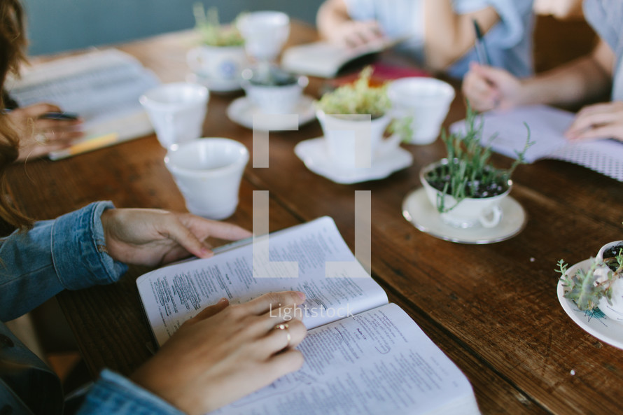 young women sitting around a table reading Bibles 