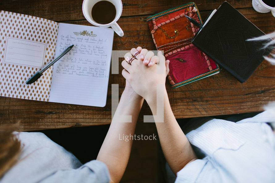 young women holding hands in prayer at a Bible study 