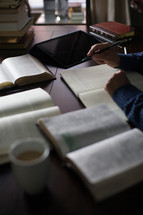 A man taking notes and studying the Bible at a desk with a cup of coffee.