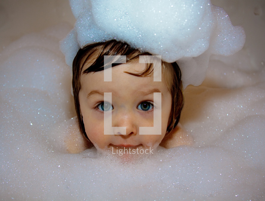 Child in the bathtub with bubbles.