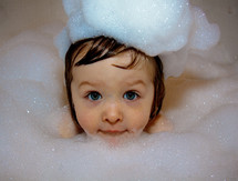 Child in the bathtub with bubbles.
