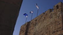 Israeli flags blowing on the top of an ancient wall
