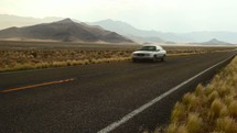 car passing driving down a desert road 