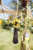 vase of flowers hanging from a tree for an outdoor wedding reception 