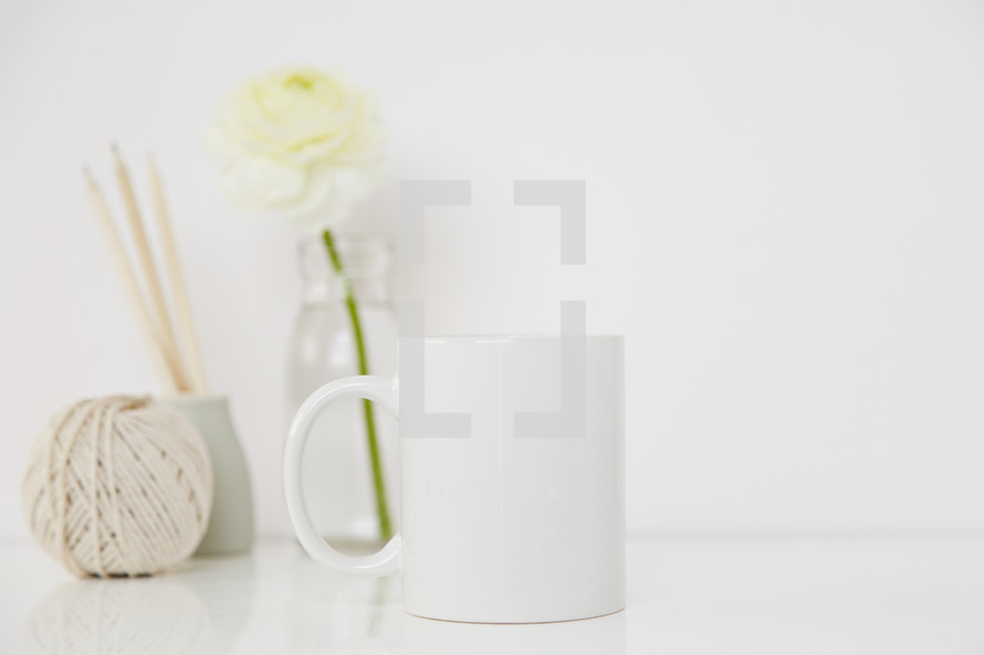 white flower in a clear vase, twine, coffee mug 