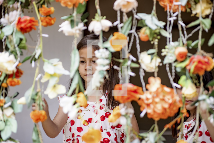 A young girl in a cherry dress looking at a wall of lighted flowers