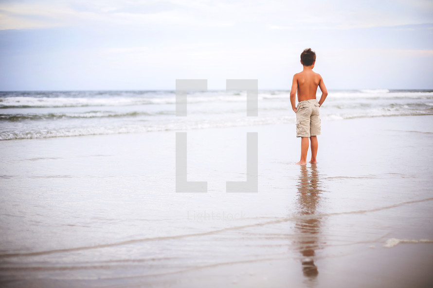 a boy standing on a beach 