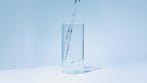 Water pouring into a glass cup with white background.