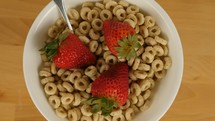 A rotating bowl of breakfast cereal with strawberries