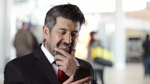 businessman in a suit texting and smiling 