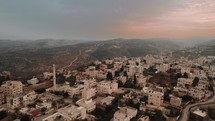 Aerial camera footage of a city with a mosque and surrounding hills in Jerusalem