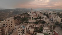 Aerial camera footage of a city with a mosque and surrounding hills in Jerusalem Drone