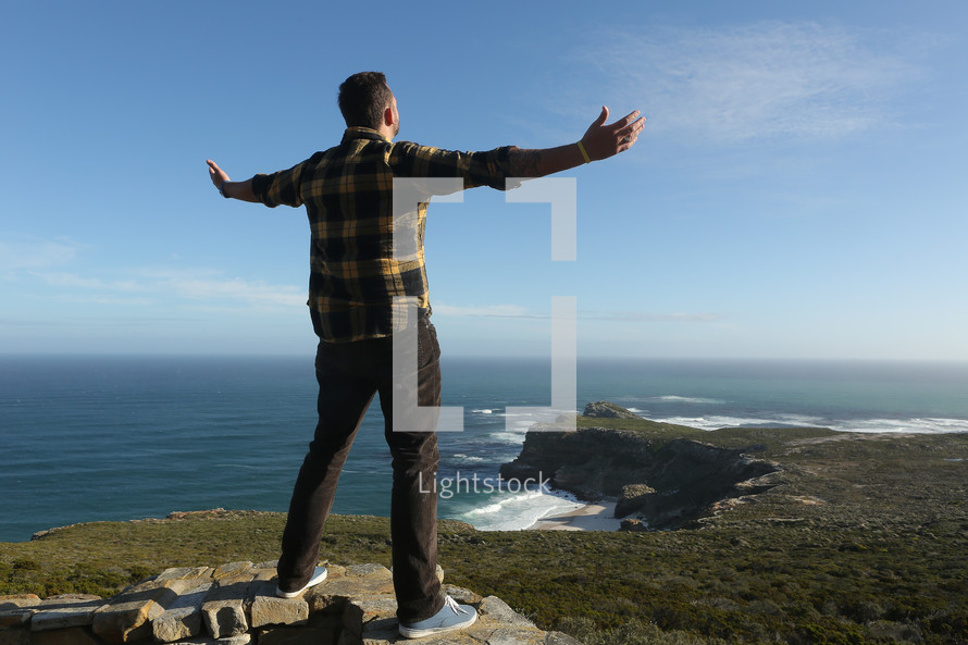 Man on mountain cliff with open arms