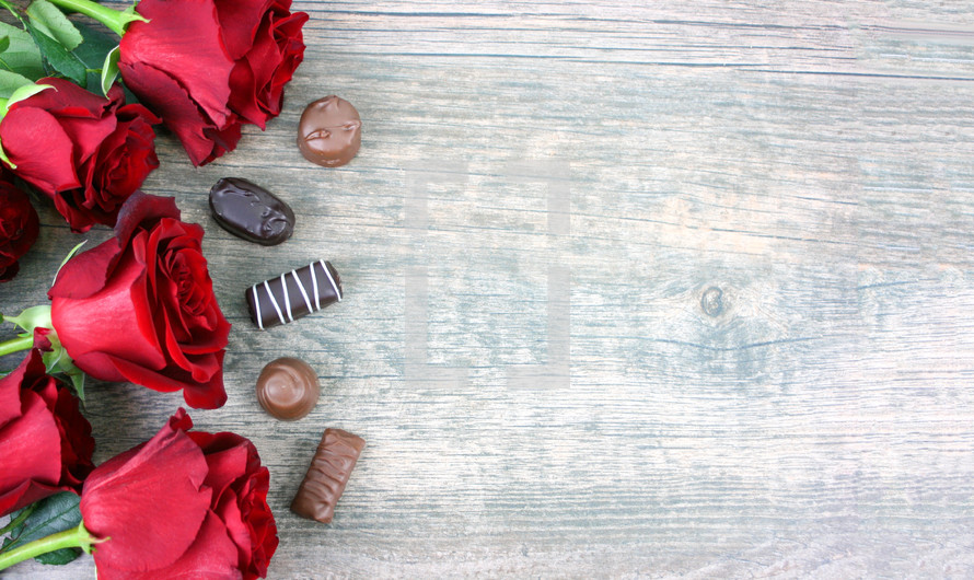 chocolates and red roses on a wood background 