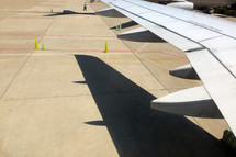airplane wing and its shadow viewed on the ground at the airport gate 