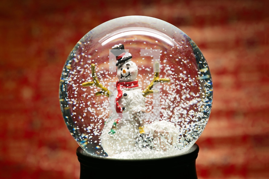 a snowman in a snow globe against a red background 