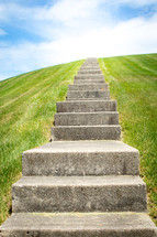 Dreamy concrete staircase leading up over green grassy hill vertical 