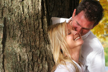 Couple leaning on a tree smiling