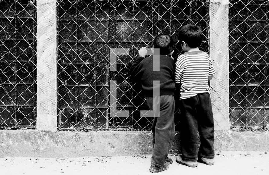 Boys looking inside window with bars