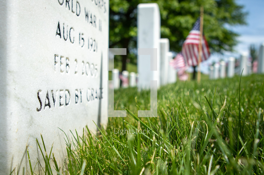 Closeup view of white Christian military gravestone memorial with American flags 
