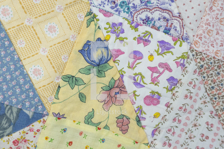 Closeup of part of a vintage patchwork quilt with triangles of floral pattern prints