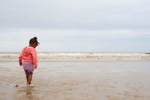 toddler girl walking on a beach 