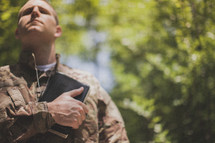 serviceman holding a Bible over his heart in prayer