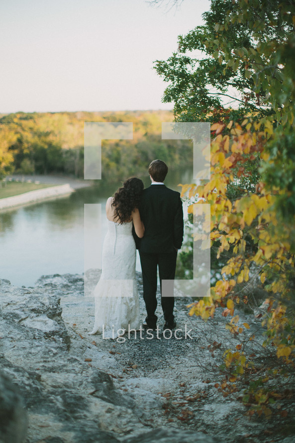 bride and groom looking out at a lake