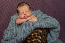 Newborn baby in blanket and wicker basket